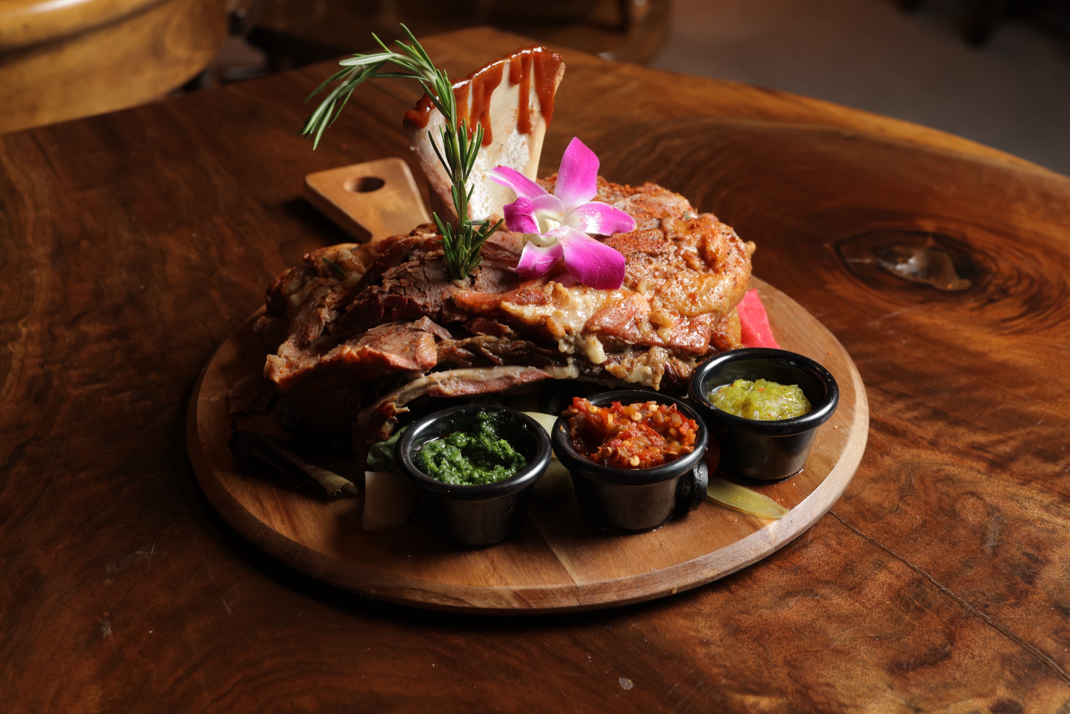 Smoked lamb platter with chimichurri and harissa on a wood paddle