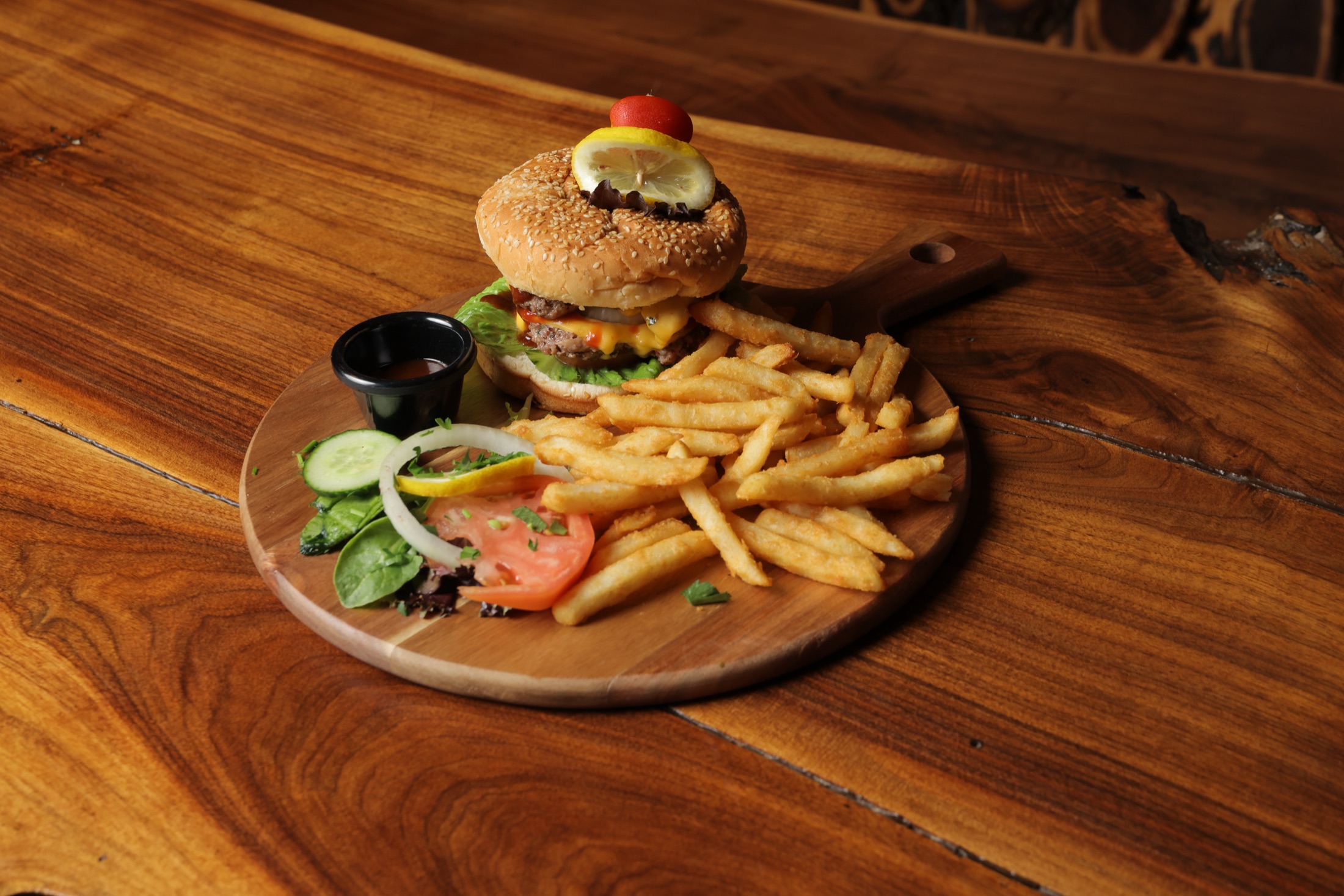 House burger and fries on a wood paddle