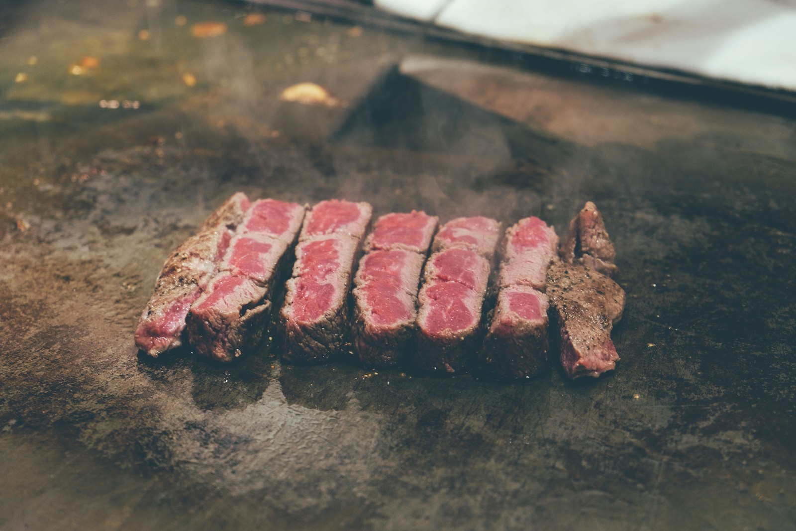 Sliced medium-rare steak on a dark board